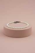 Lamù bracciale acciaio con perline bianche su piedistallo rosa cipria