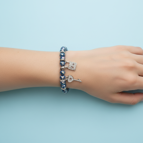 Bracciale perle vetro blu con ciondoli chiave e lucchetto indossato su polso singolo