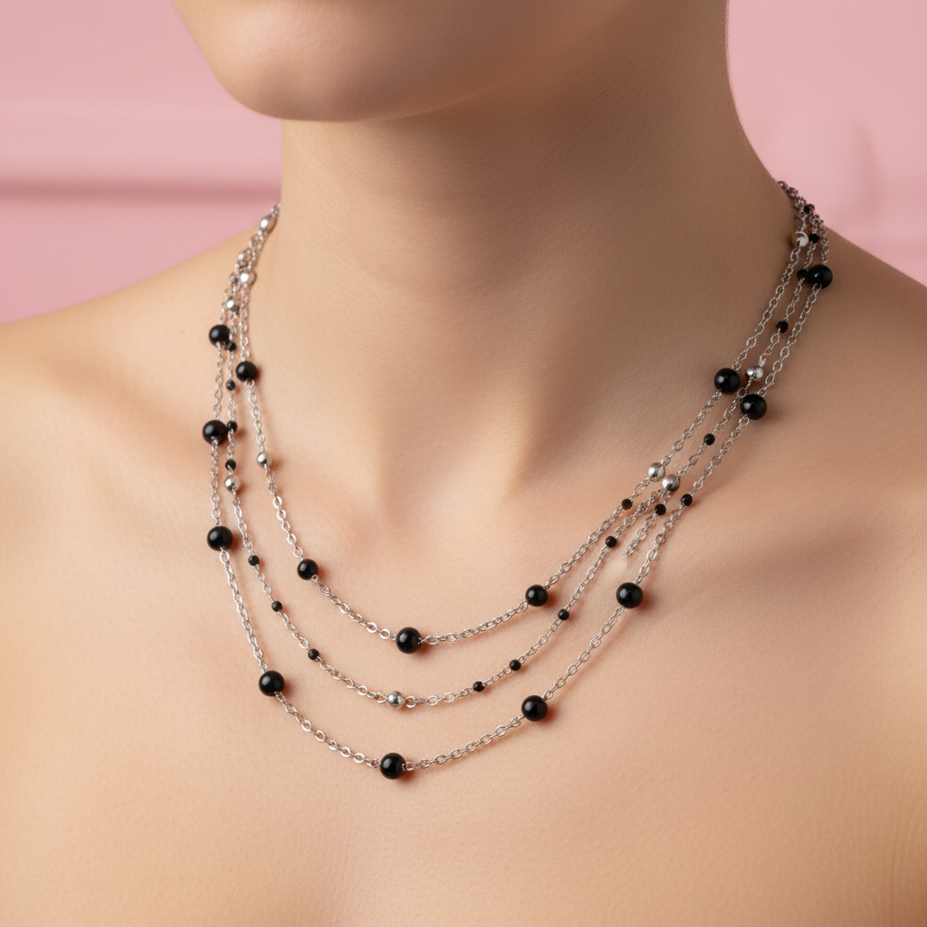 Collana multifilo sfere nere indossata sfondo rosa cipria