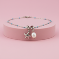 Collana stella marina perla turchese su piedistallo rosa cipria